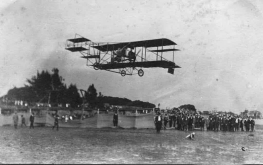 Alameda Post - an early aeroplane flies over a crowd at Sunset Field