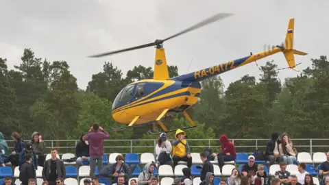 Getty Images Visitors ride in a yellow Robinson helicopter during a motorsport festival in Russia.